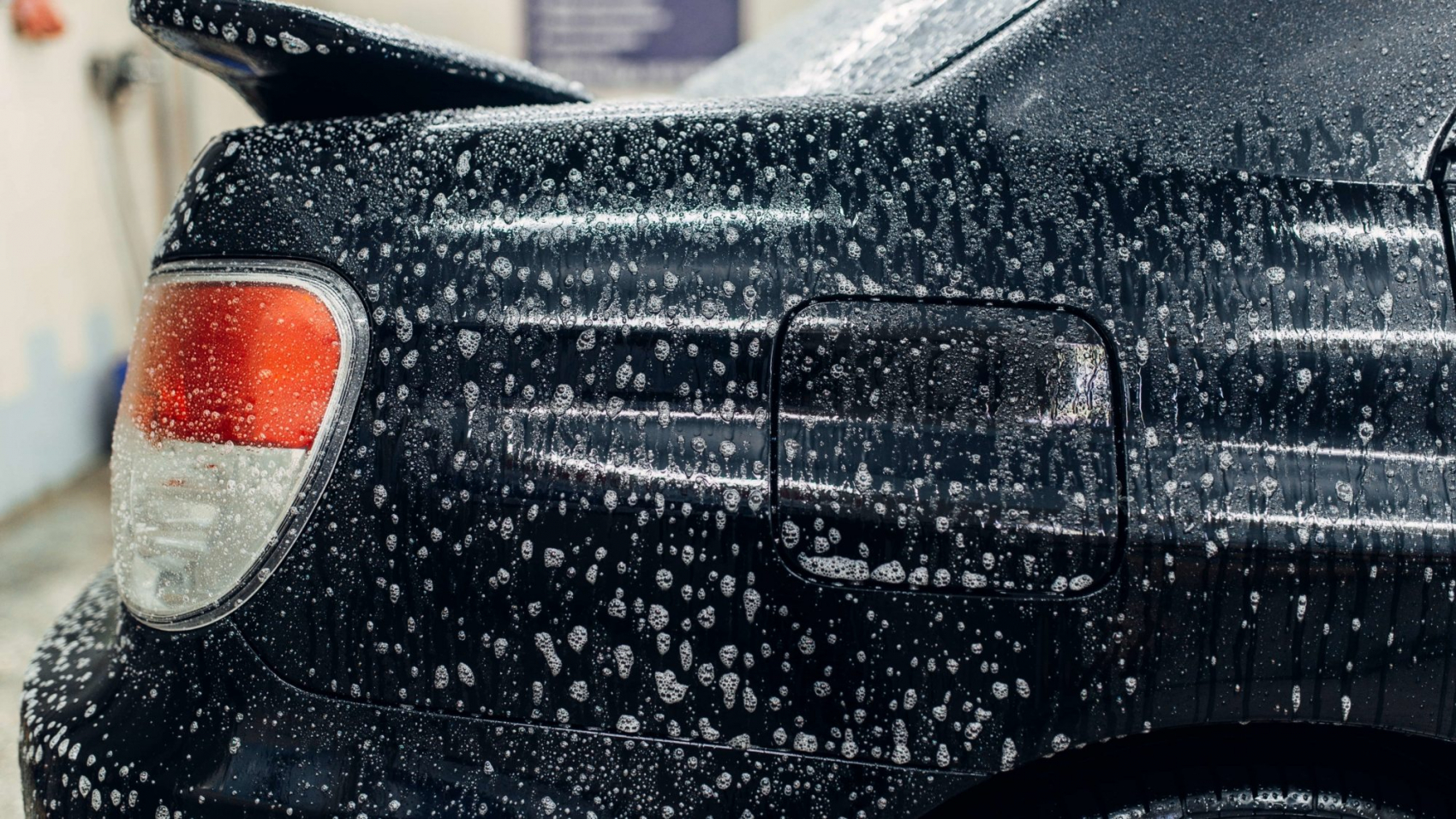 Carwash service, car in foam, side view. Auto detailing, high pressure contactless washing on special station